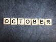 Letter tiles on black slate background spelling October