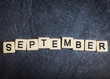 Letter tiles on black slate background spelling September