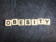 Letter tiles on black slate background spelling Obesity