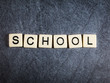 Letter tiles on black slate background spelling School