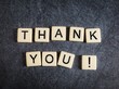 Letter tiles on black slate background spelling Thank You!