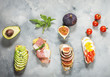 A set of avocado sandwiches, cherry tomatoes and eggs, figs, prochutto on a concrete background