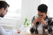 Two people sitting at the desk in office room. Advisor holding pointing at resume paper, stressed diffident African candidate woman during interview. Human resources, recruitment and hiring concept