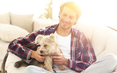 handsome guy with a dog sitting in a large armchair.