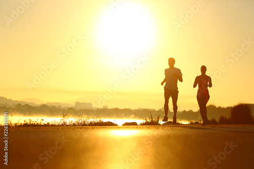 Man and woman silhouettes running at sunrise Obraz na płótnie
