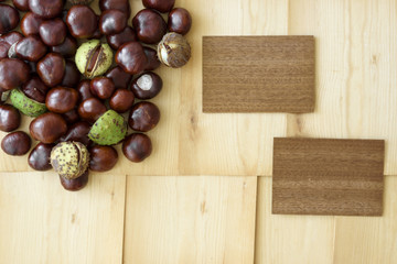 Scattered chestnuts and two wooden cards arranged on light wood background involving copy space.