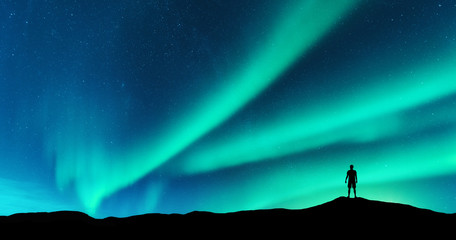 Wall Mural - aurora and silhouette of alone standing man on the hill. lofoten islands, norway. aurora borealis an