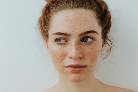 woman portrait. close-up. beautiful blue eyed girl with freckles is looking away, on a white backgro