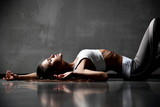 Fototapeta  - Young sporty beautiful sexy woman posing lying on floor in elastic sport cloth looking up
