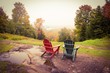 Two empty adirondack chairs overlook a foggy valley with fall color