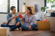 Asian young couple are clinking coffee cups after successfull packing the big cardboard box for moving in new home, Moving and House Hunting concept,