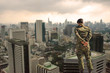 Back view. Soldier in camouflage uniforms, hands behind his backs on urban city background,democracy security concept.