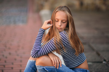Wall Mural - young teenage poses to photographer. blonde girl in jeans and blouse