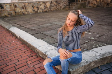 Wall Mural - young teenage poses to photographer. blonde girl in jeans and blouse