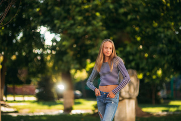 Wall Mural - blonde teenage girl in striped blouse on the backgrountd of green tree
