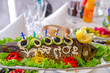 Whole stuffed fish on an oblong dish, decorated with lemon, vegetables and olives. A traditional Jewish dish or banquet dish. Selective focus.