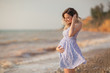 Pretty young pregnant woman posing on the beach by the sea.