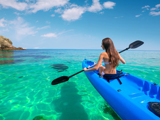 Wall Mural - Beautiful young woman kayaking in the sea near the islands. Adventure by kayak.