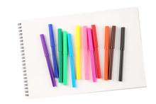 Top view of a set of twelve colorful felt tip markers on a blank scetchbook isolated on white background