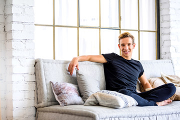 A young handsome man relaxing on the sofa in a loft style apartm