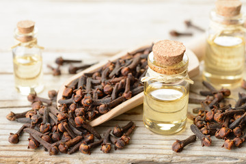 Wall Mural - clove essential oil in the glass bottle, on the wooden board