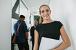 © Jacob Lund - Happy woman in office corridor with coworkers at back