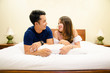 © bellito10 - asian couple lying together on bed and talking
