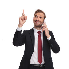 happy businessman on phone points finger and looks up