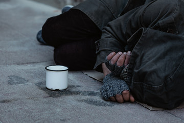 Wall Mural - Homeless man lies on the street in the shadow of the old building and begging for help and money. Problems of big modern cities. Close up.