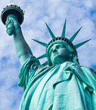 Fototapeta Nowy Jork - Estatua de la libertad, vista desde un ángulo bajo, con fondo nublado y cielo azul, en la Isla de la Libertad de Nueva York, EE. UU.,