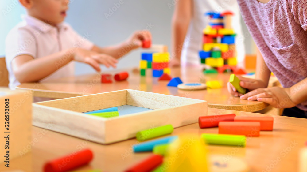 Children playing with colorful wooden didactic toys at kindergarten - obrazy, fototapety, plakaty 