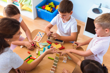 Wall Mural - Preschool teacher with children playing with colorful wooden didactic toys at kindergarten