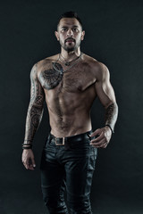 Handsome fit man posing wearing in jeans with tattoo. Tattoo art. Man handsome shirtless muscular with jeans over dark background. Muscular tattooed athlete look attractive. Sport and fashion concept