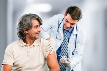 Wall Mural - Handsome doctor making vaccination to male patient