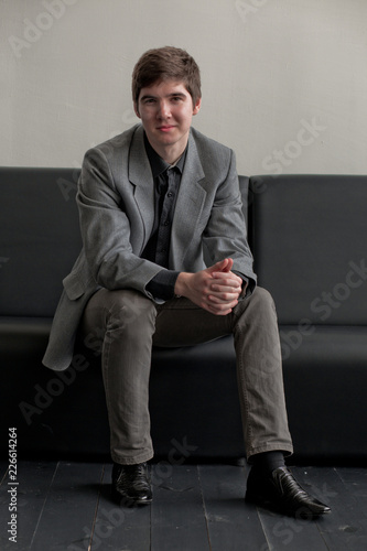 Handsome Young Man In Suit Sitting On Couch In Reception Business