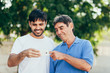 © kleberpicui - Smiling son and father using mobile phone outdoor