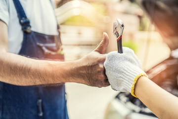 Mechanic hand checking and fixing a broken car in  garage.hand of mechanic with thumbs up and tool