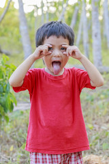 Asian Thai little boy rounding his eyes with his fingers