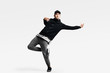 © Leika production - Handsome young man wearing a black sweatshirt, gray pants and a cap dancing street dances on a white background