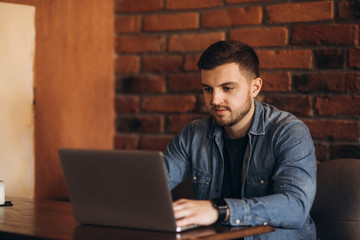 Young programmer working on a laptop in a cafe