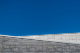 Fototapeta Na sufit - Geometric detail of a modern building with two walls, white and black, facing the background of a blue sky.