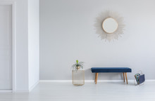 Gold Mirror On The Wall Above Blue Bench In Minimal Empty Entrance Hall Interior With Plant. Real Photo