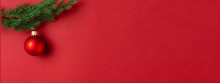 Evergreen Branch With Red Christmas Ball On Red Background. New Year Banner With Place For Text.