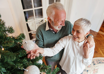 Wall Mural - Elderly couple decorating a Christmas tree 