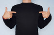 man pointing at his t-shirt can be used as a clothes design template on a blue background. T-shirt with long sleeves black. mocap for design.