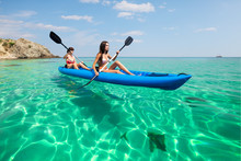 Two Young Women Kayaking In The Sea. Beautiful Woman Canoeing On The Island On A Summer Day.