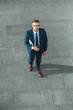 © LIGHTFIELD STUDIOS - high angle view of handsome middle aged businessman holding coffee to go and looking at camera on street