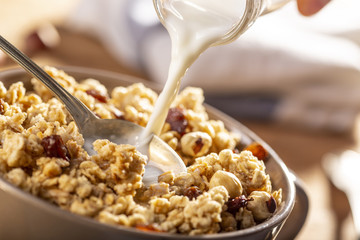 Pouring milk in a bow of organic hazelnut granola