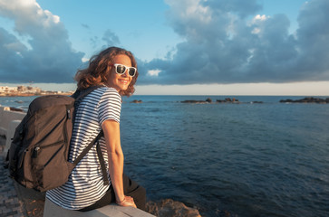 Beautiful happy young woman at seaside resort with sunglasses laughing in the rays of the sun