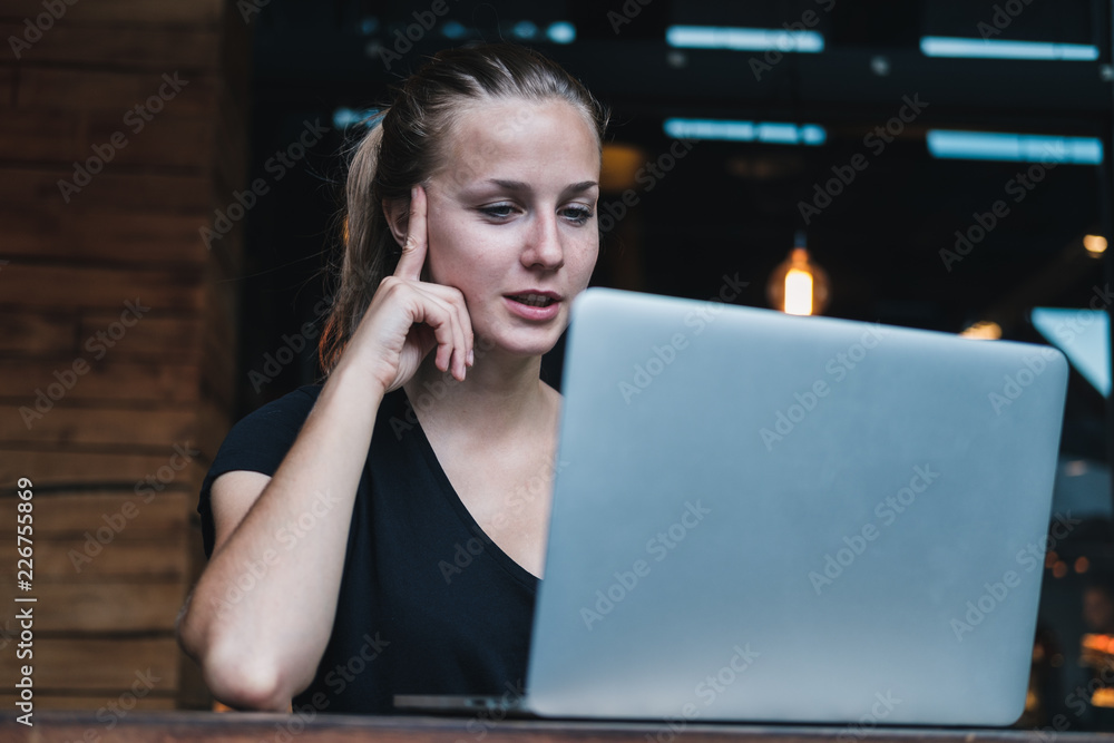 Beautiful smiling girl using laptop or computer in cafe to chat on video call. Horizontal  - obrazy, fototapety, plakaty 